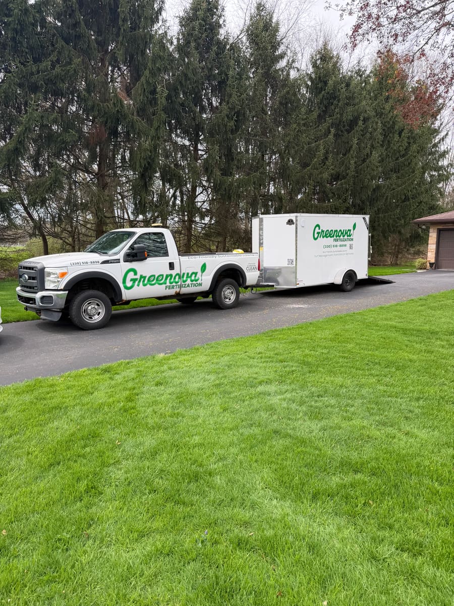Two Greenova Fertilization service trucks parked on a residential street