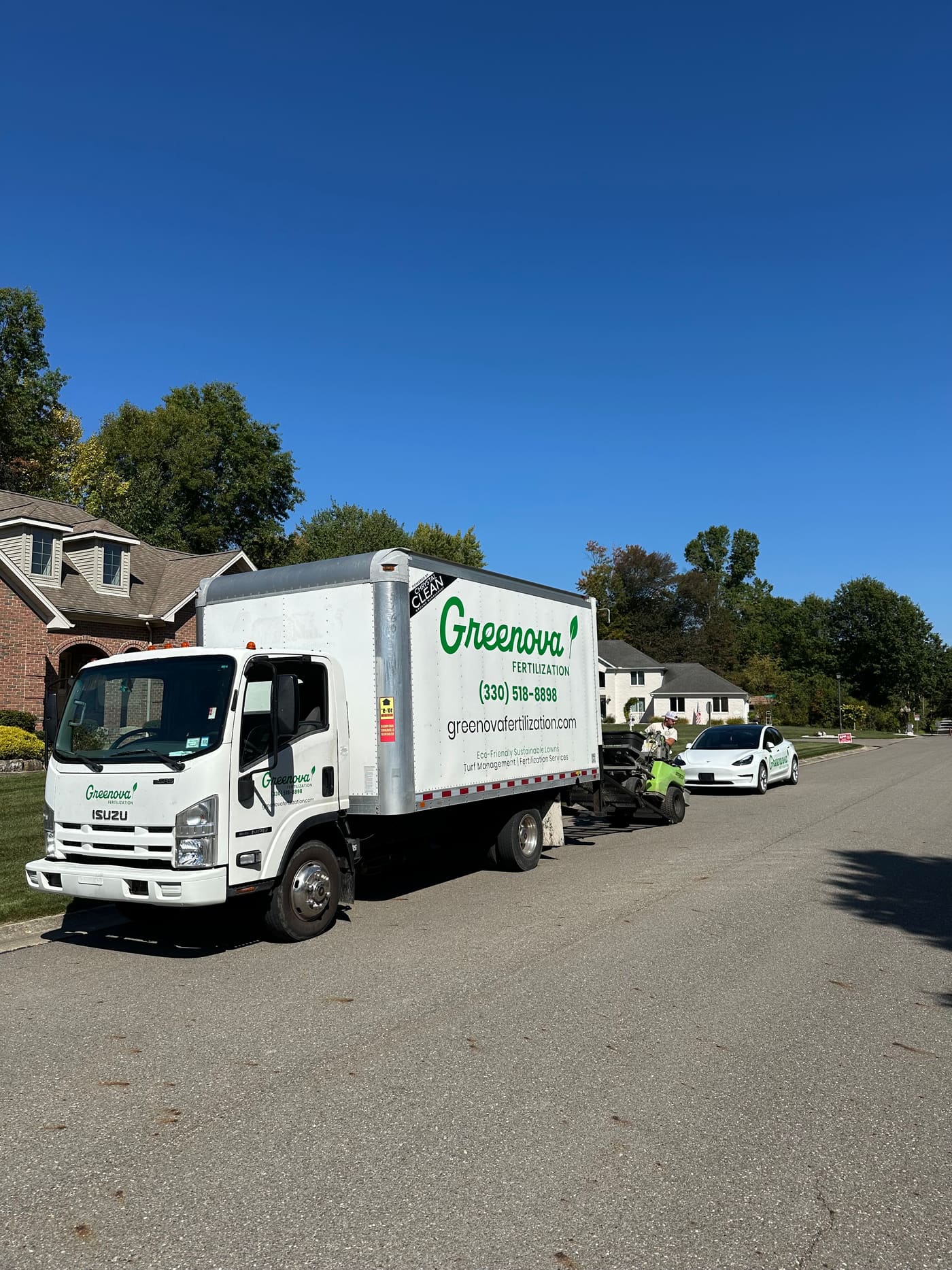A Greenova Fertilization truck and trailer parked in a driveway between service stops